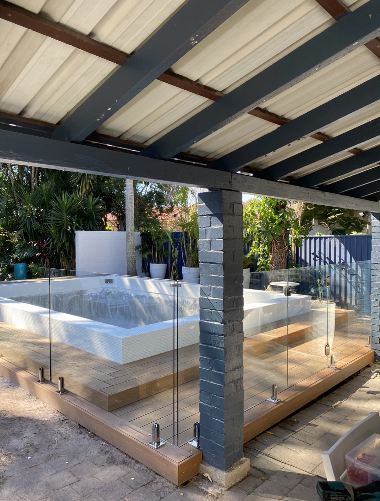 Frameless glass pool fence on spigots around a raised plunge pool on a timber deck