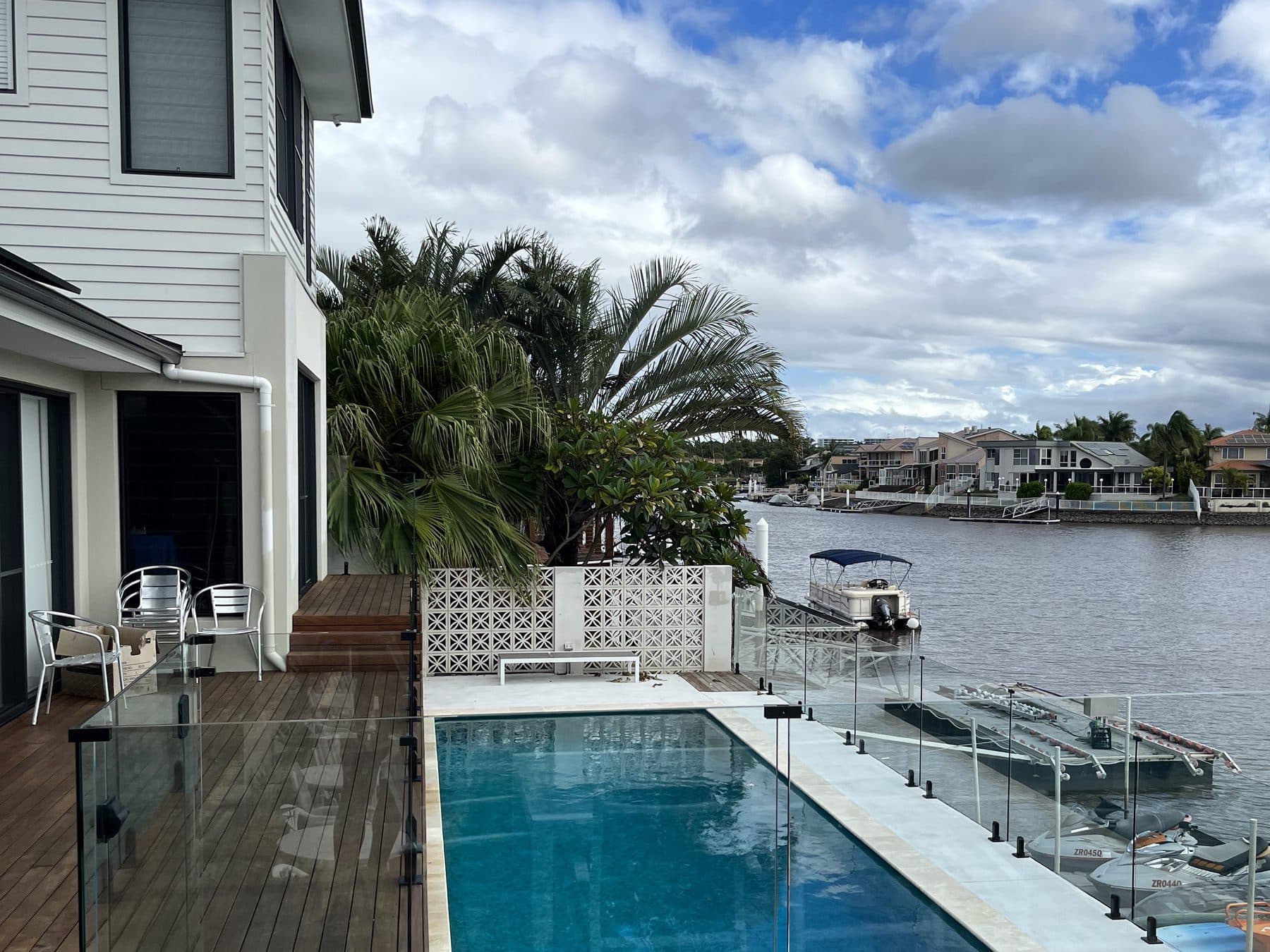 Frameless glass pool fencing on a canal-front property, with a pontoon and the waterway behind