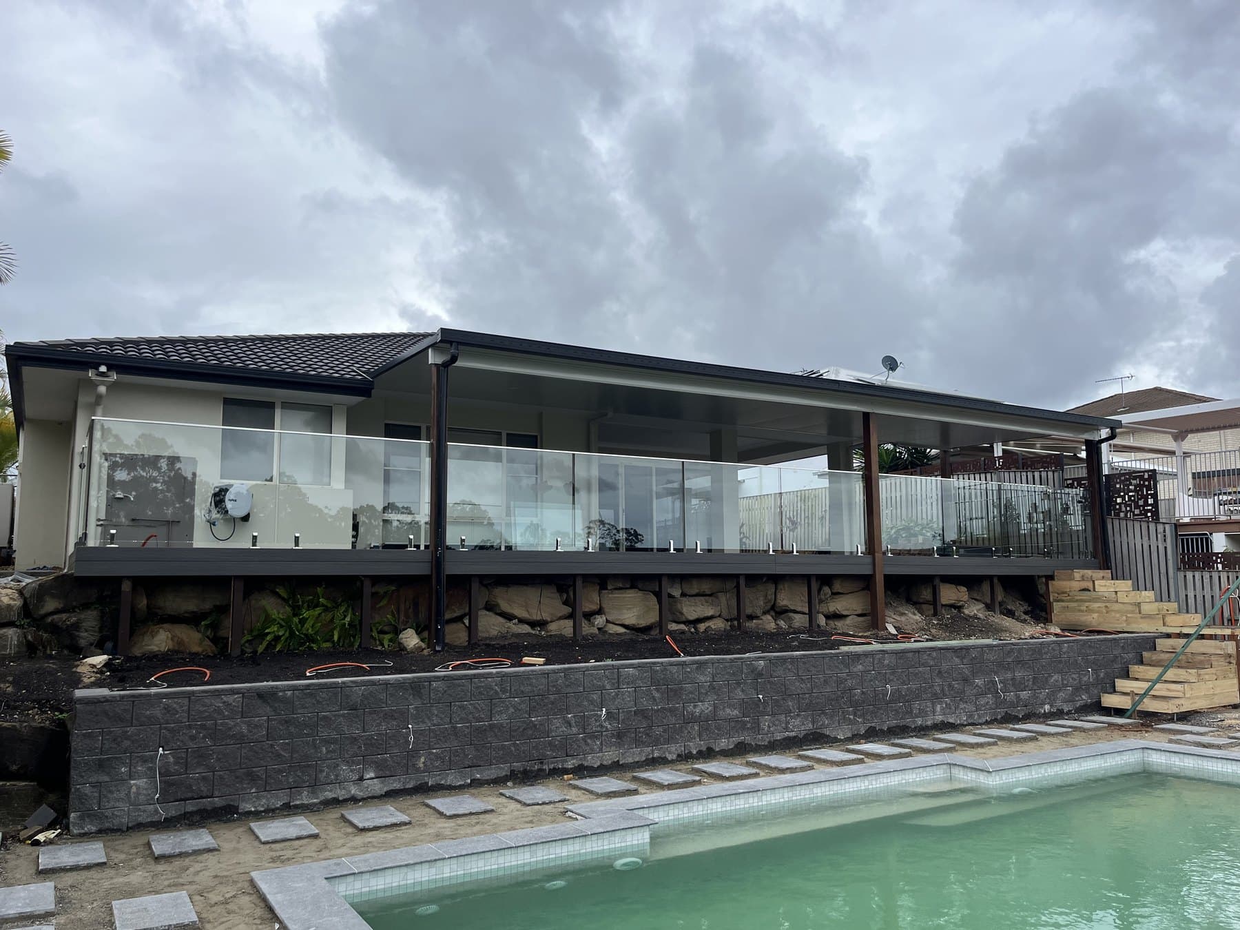 Charcoal block retaining wall supporting a deck above a pool