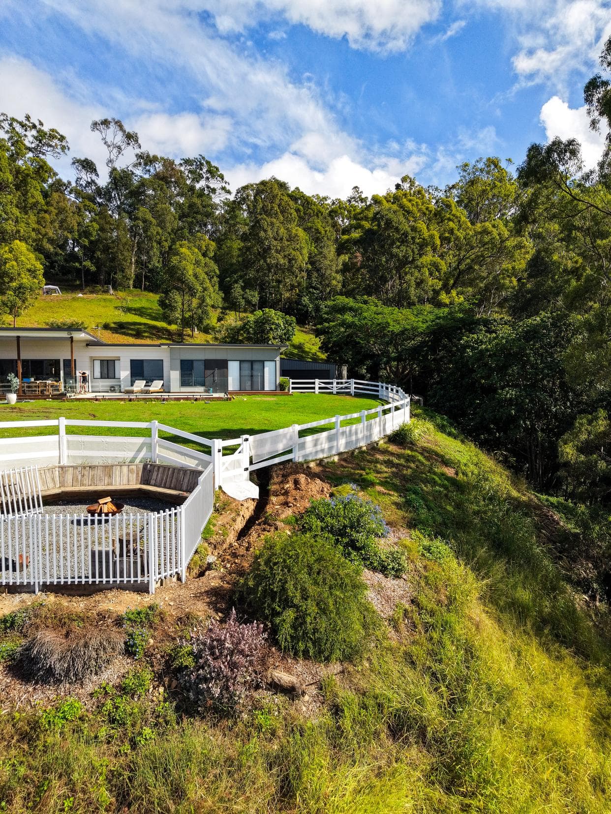 White post and rail fencing sweeping around an acreage ridge with hinterland valley views behind